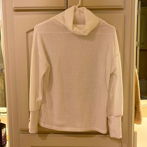 Creamy white turtle neck with three gold buttons on each sleeve.